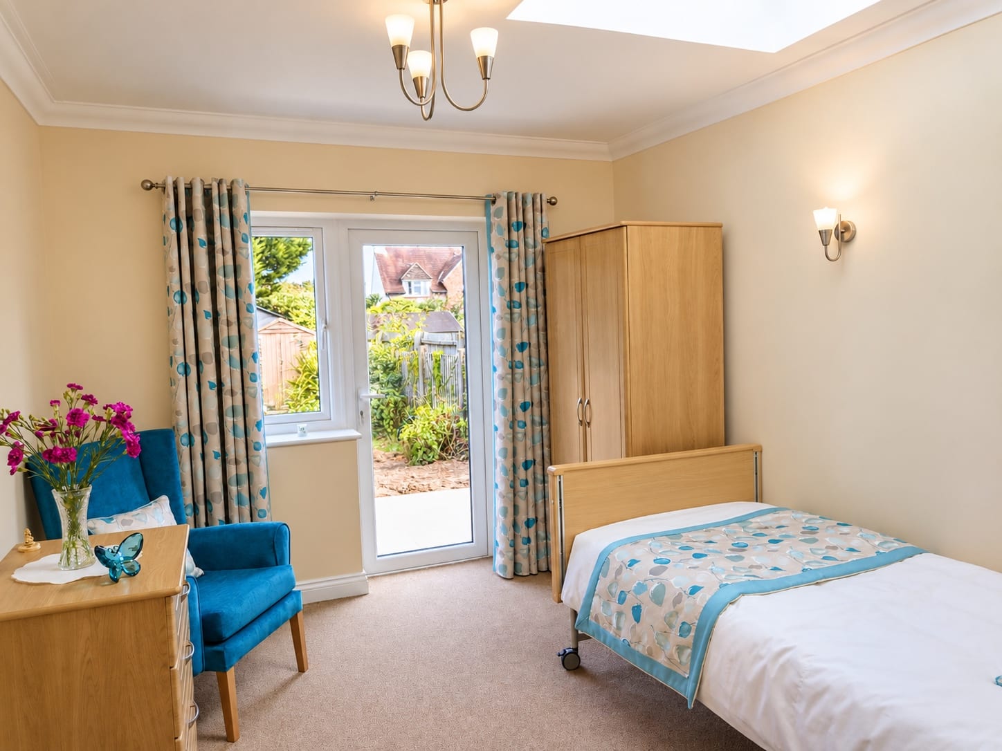 A bed, a blue armchair, a wardrobe and patio doors to the garden.
