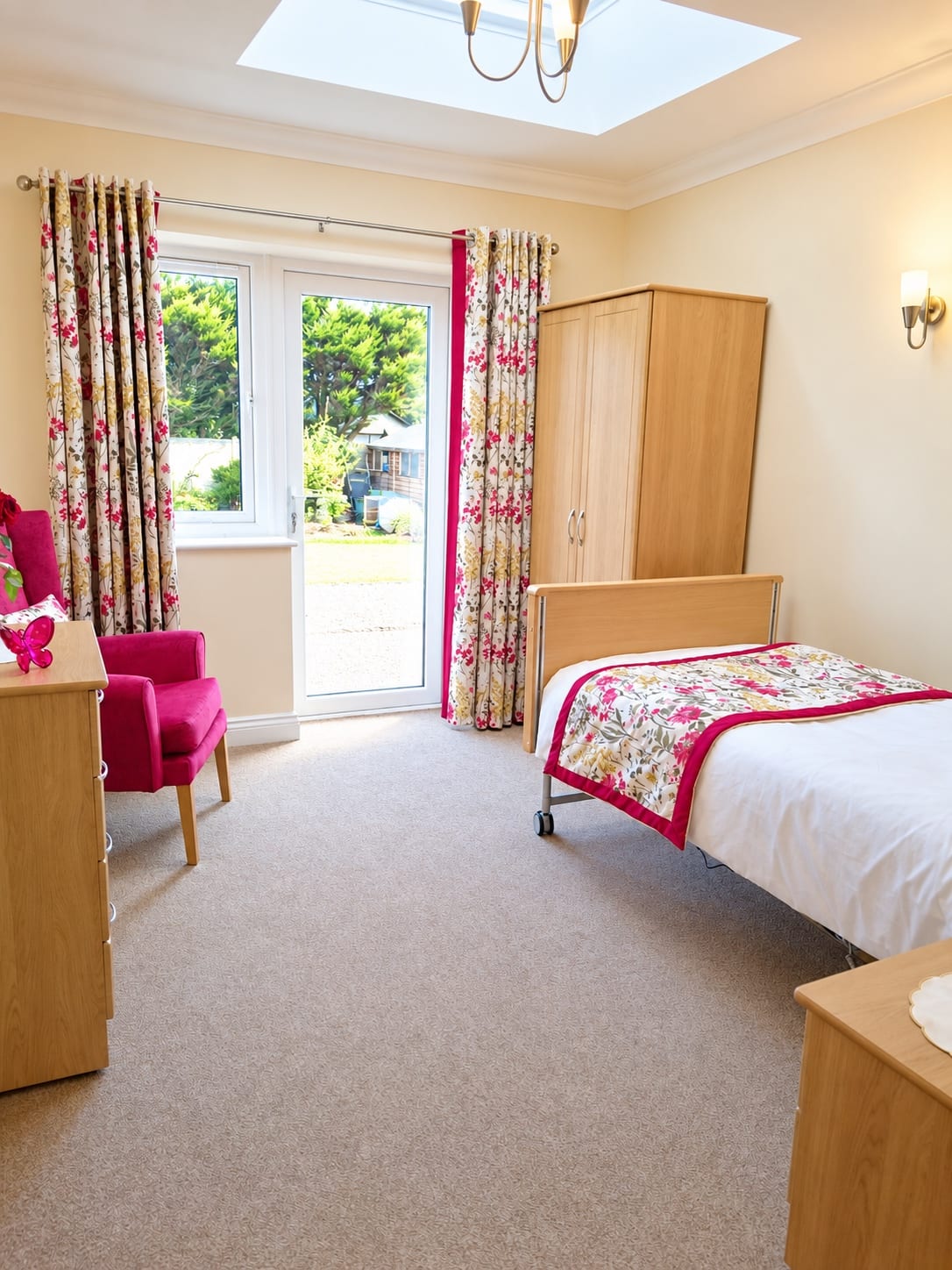 Patio doors with floral curtains, an armchair, a wardrobe and a bed under a skylight.