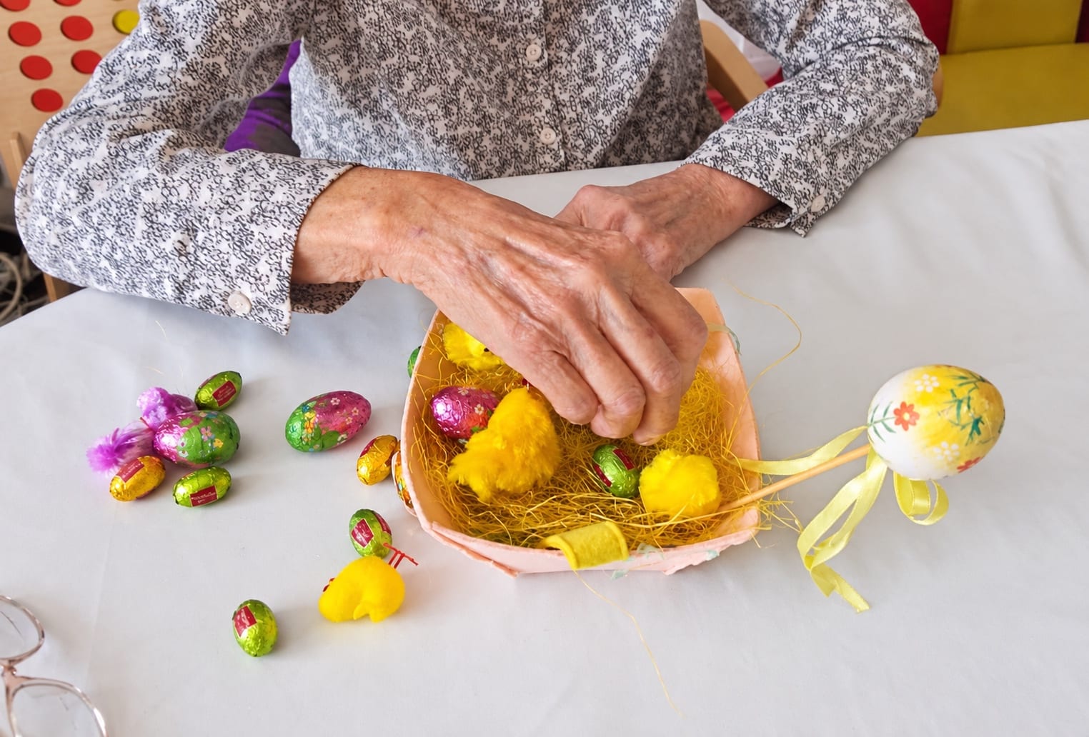 Hands filling an Easter basket with chocolate eggs and yellow chicks.